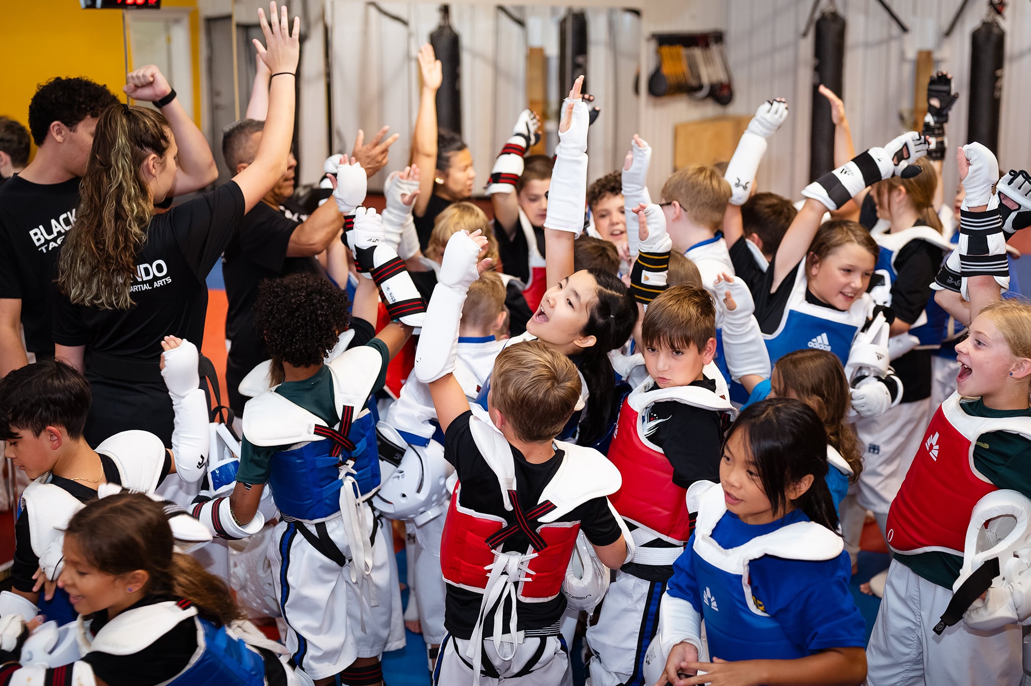 a group of child members in sparring uniform cheering in a huddle