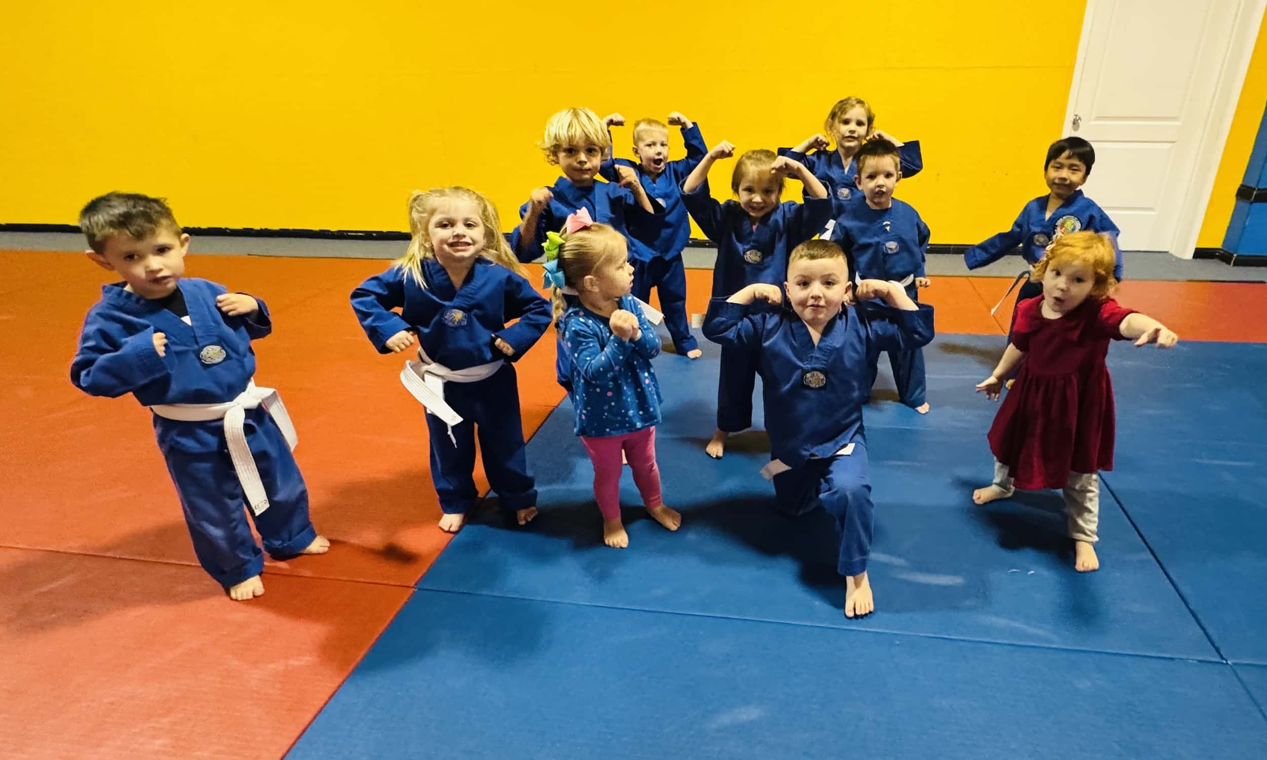 a class of children in blue gi flex for the camera