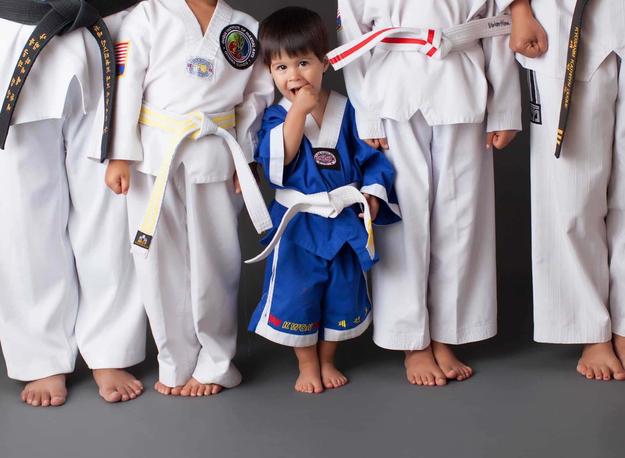 Stock image of a young child in a blue gi standing between members in white gi